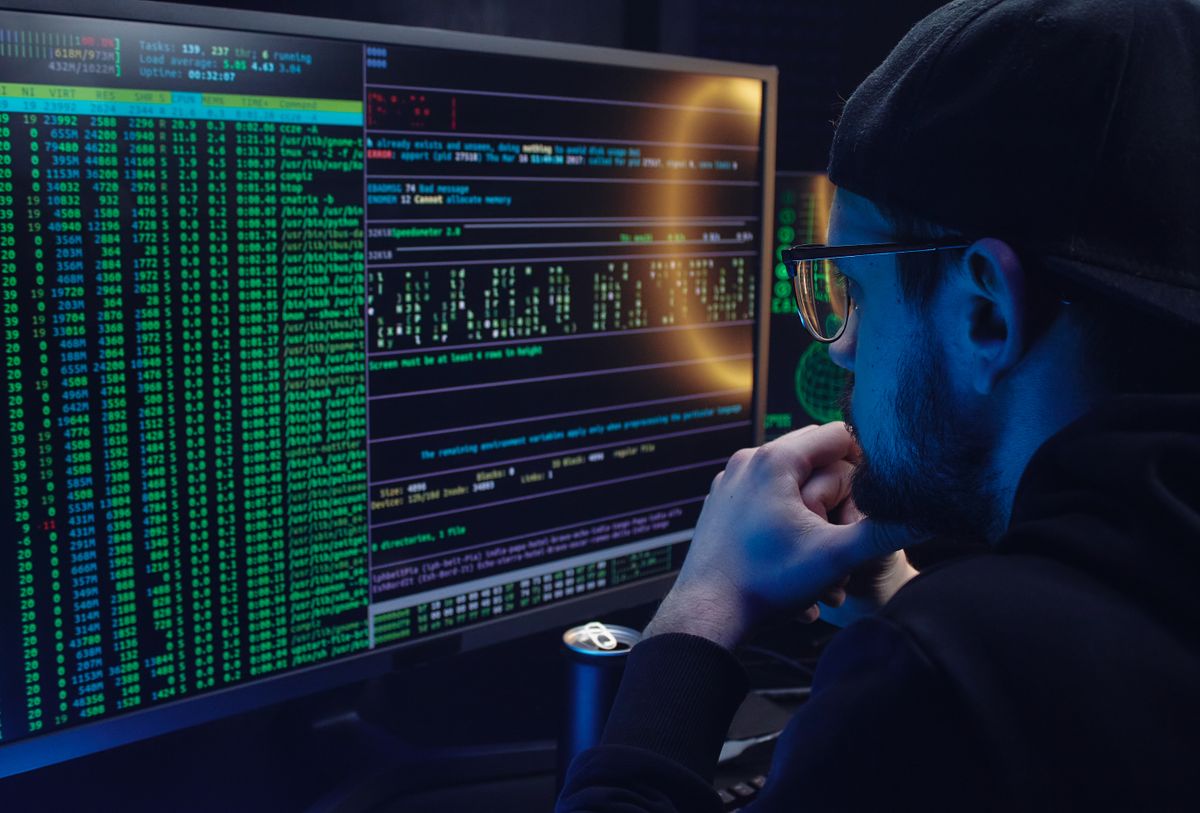Person examining system activity across computer monitors.