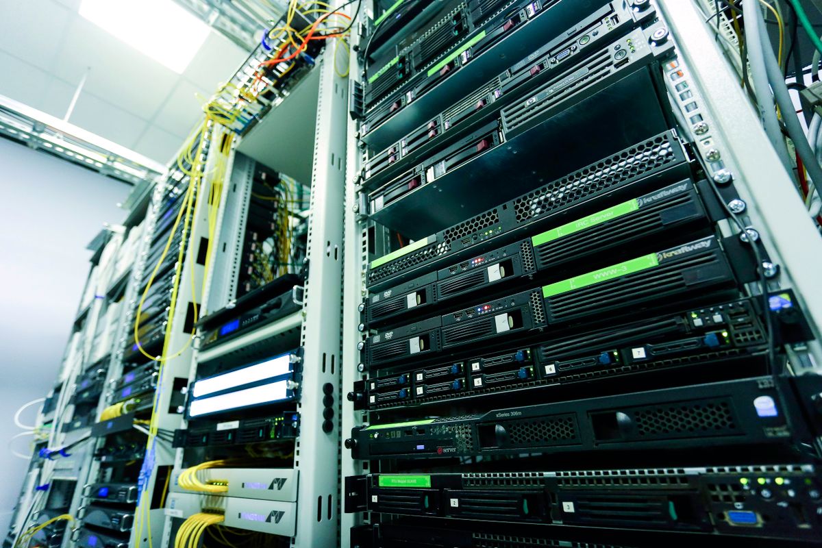 Rows of rack-mounted servers and network equipment connected by yellow cables.